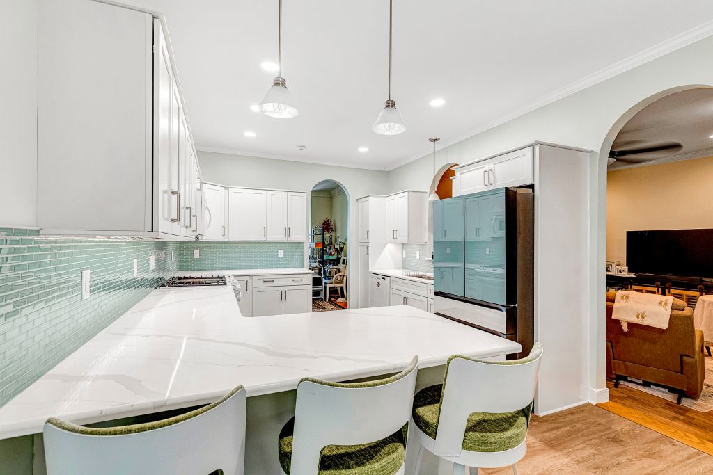 Kitchen Remodel with light blue cabinets, wood floors, stainless steel appliances, and marble countertops.